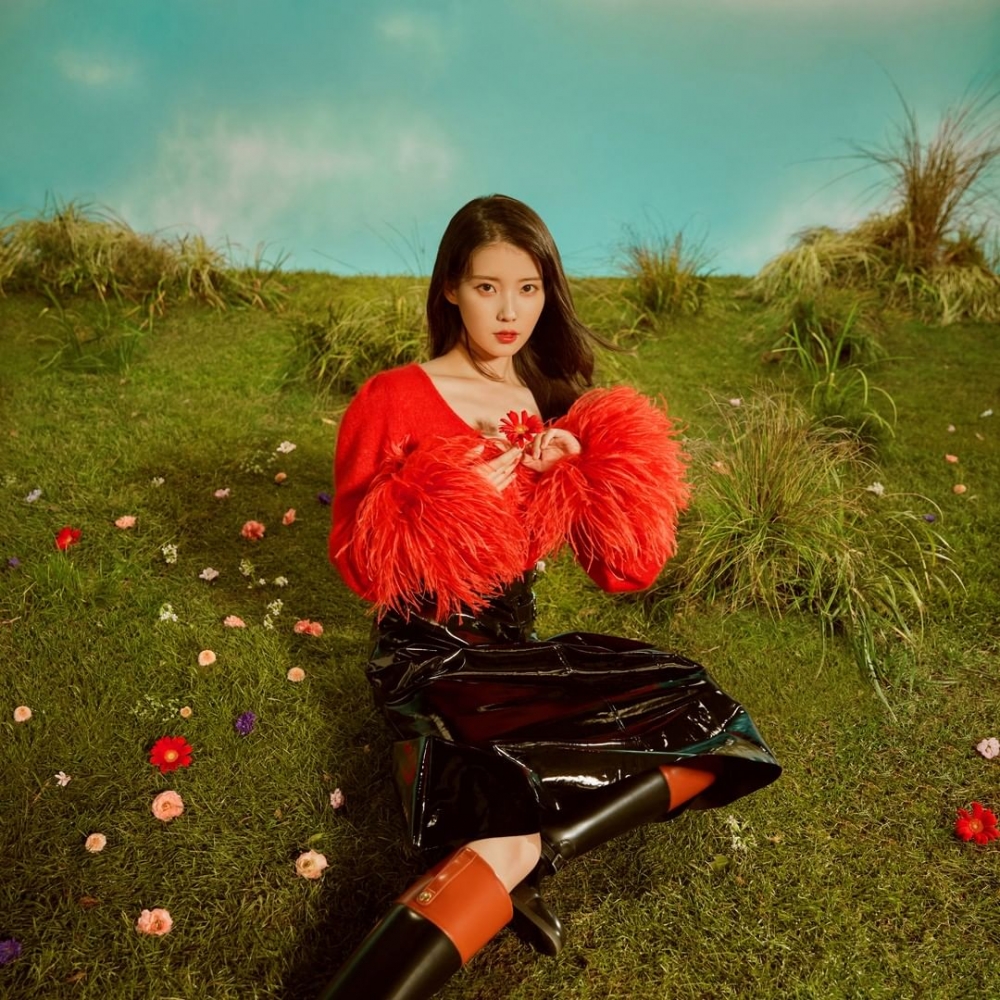 被稱為「人間Gucci」的IU,身穿紅色帶有羽毛紅色毛衣配搭黑色亮面革皮長裙與長靴,營造嬌貴氣質。