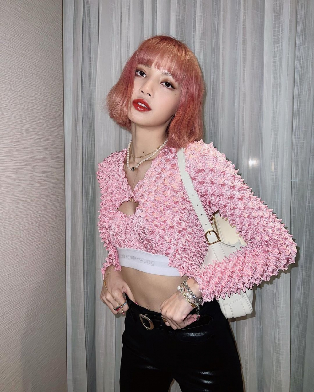 BLACKPINK成員Lisa染了一頭浪漫夢幻的草莓粉髮色,配搭粉色緞面短款外套造型展現腰部線條,少女感十足。