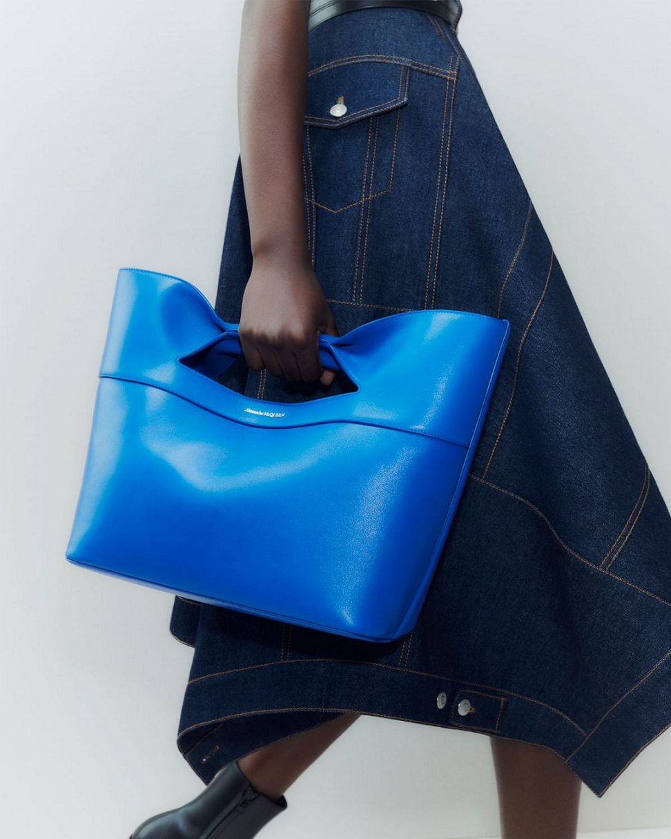 模特兒手提著The Bow Small in Electric Blue。