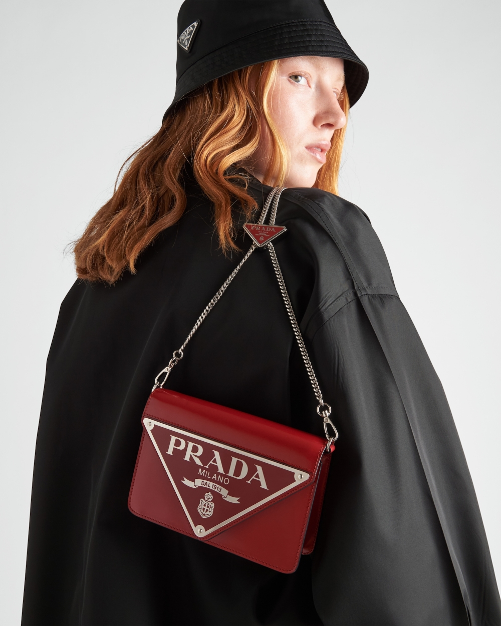 模特兒演繹猩紅色拋光皮革掛肩袋。