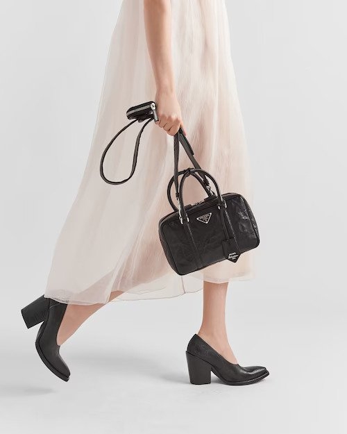 模特兒演繹Medium Antique Nappa Leather Top Handle Bag-Black。