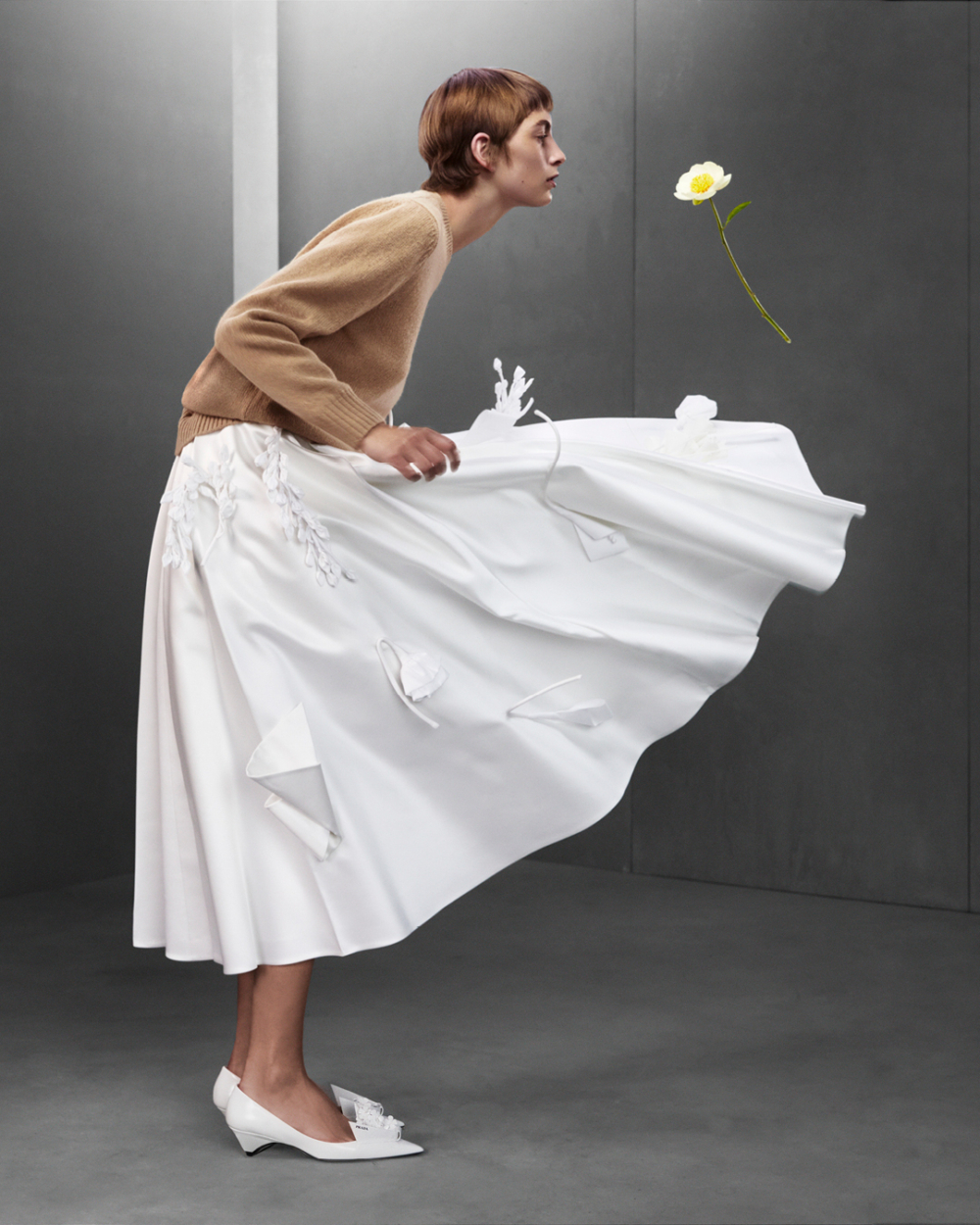 在Prada 2023 秋冬系列裡,前衛花卉雕塑躍上白色長裙、鞋履以及復古風格的手袋上