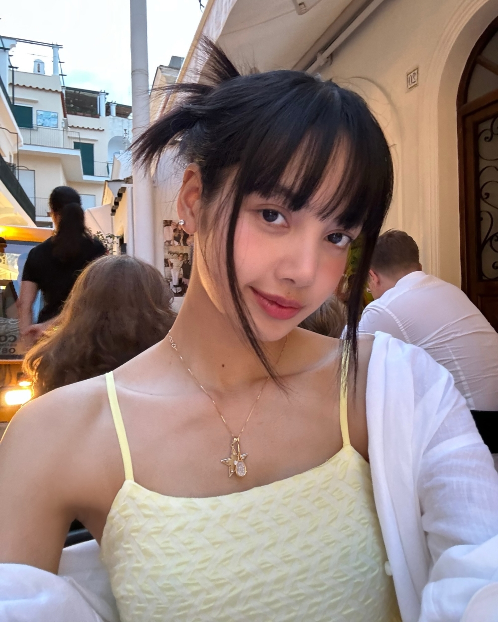 Lisa隨性的扎起頭髮,身穿一件簡單的細肩帶黃色洋裝