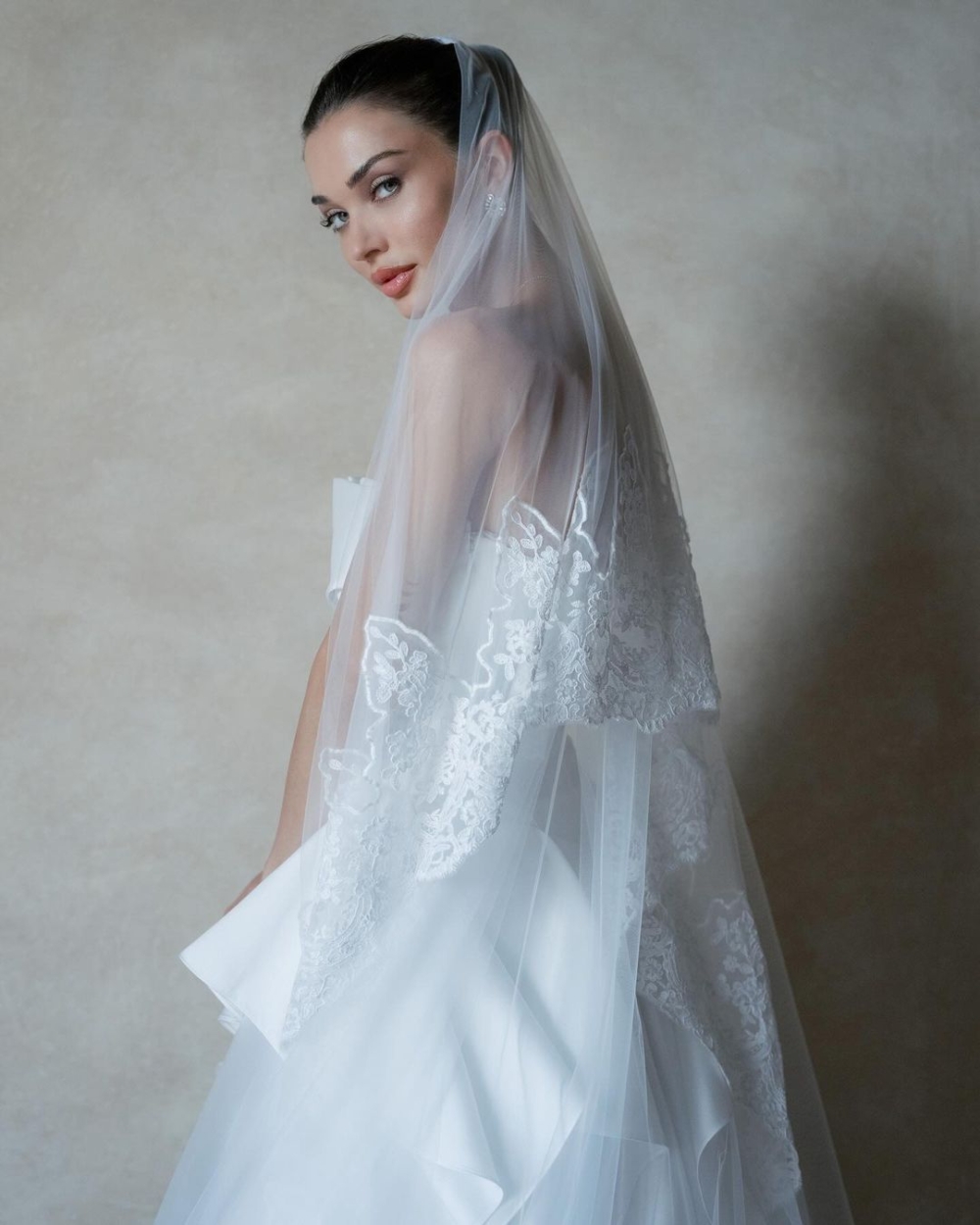 緊身胸衣搭配胸前的花瓣型領口，整件婚紗以真絲製成，下半身則是帶有荷葉邊的寬大裙襬