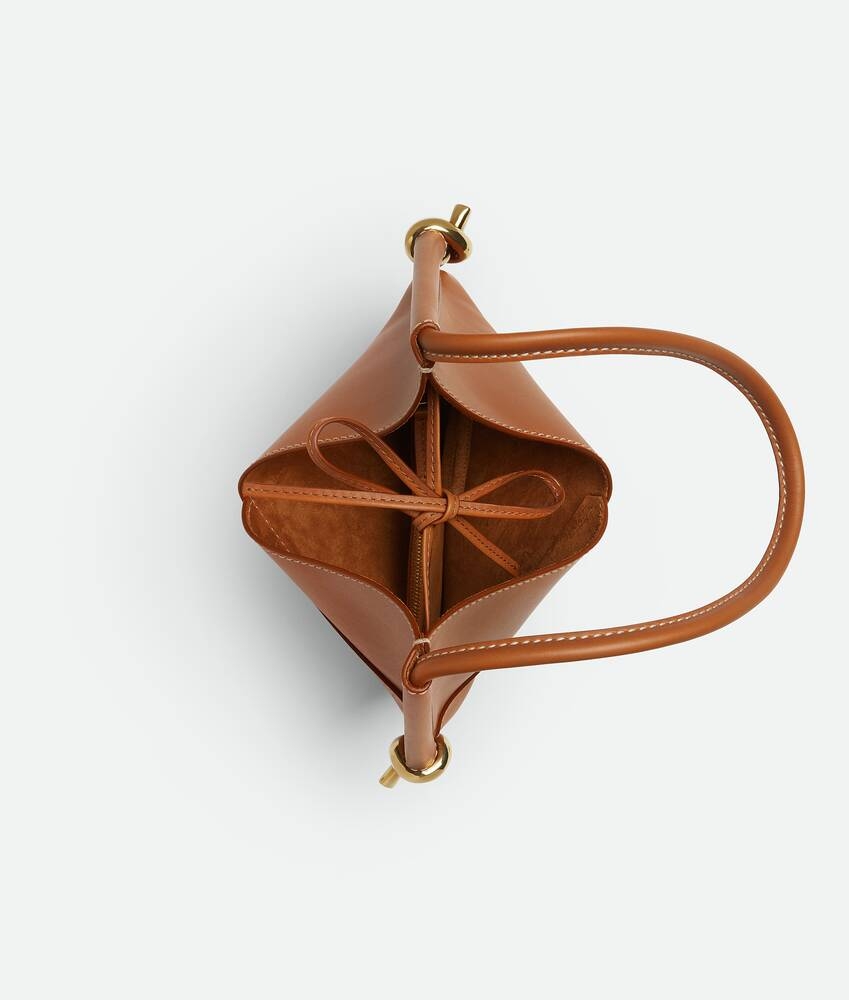 包包設有標誌性結飾細節，皮繩閉合設計簡潔實用