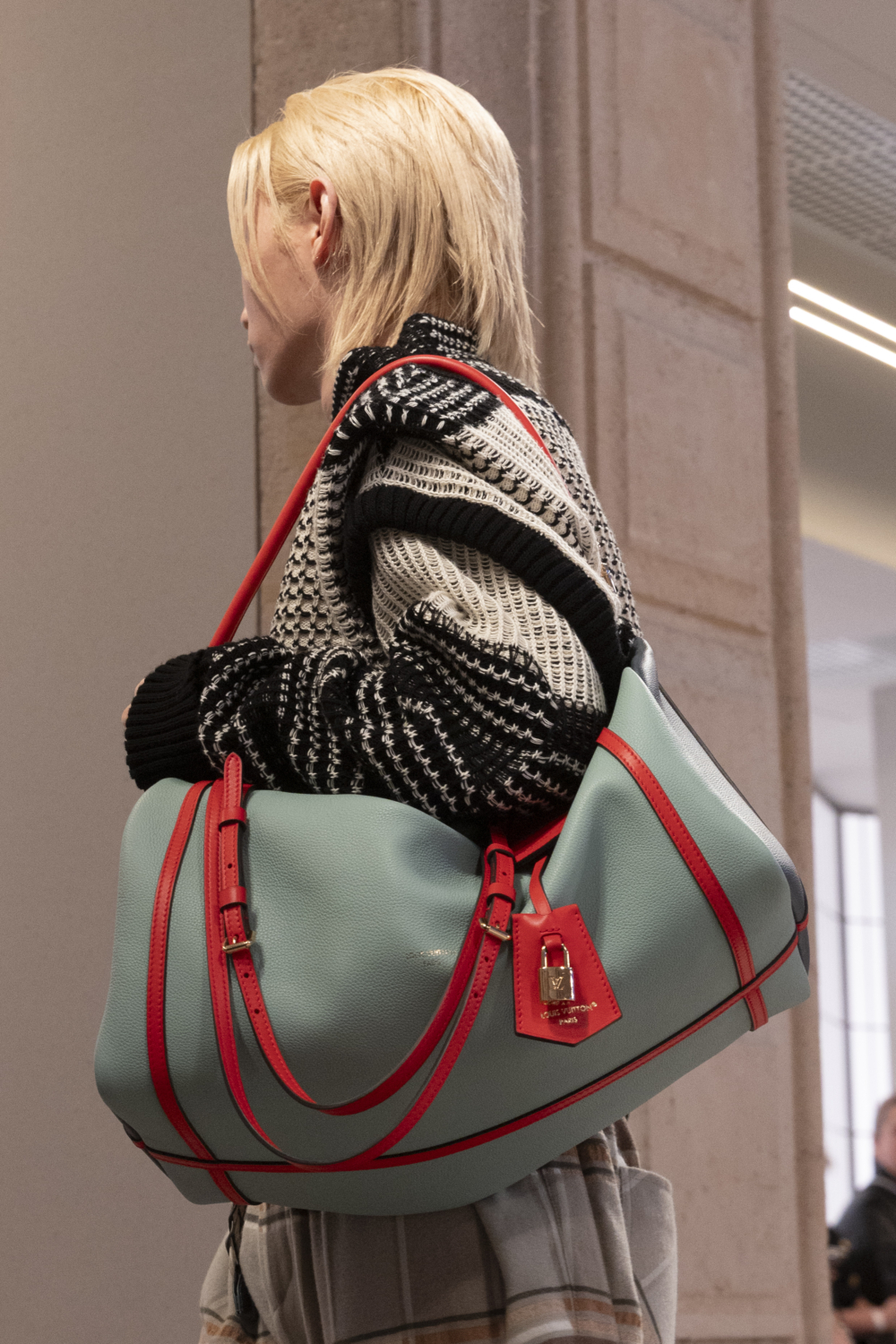 Stray Kids成員Felix身著一款藍紅相間的旅行手袋