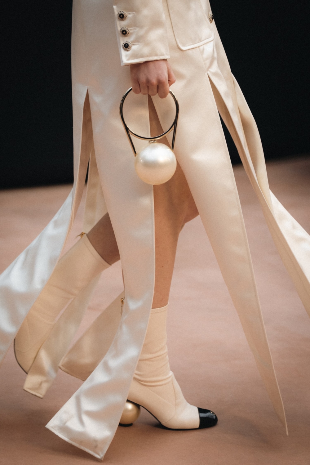 以大型珍珠為核心，搭配金屬環與「CHANEL」字樣