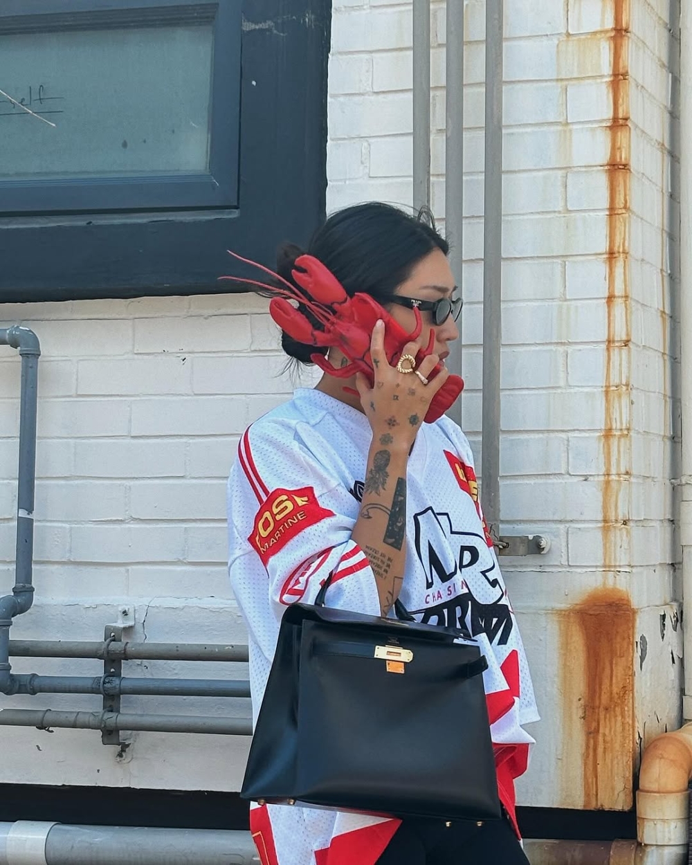 Peggy上身這款經典的黑金配色Kelly Bag，搭配運動風十足的球衣、黑色單車褲，將正式優雅搭配街頭率性，展現衝突風格美感