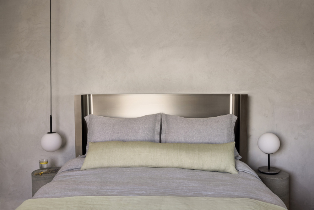 臥室以不鏽鋼床頭板搭配柔和亞麻寢具與簡約球形吊燈。