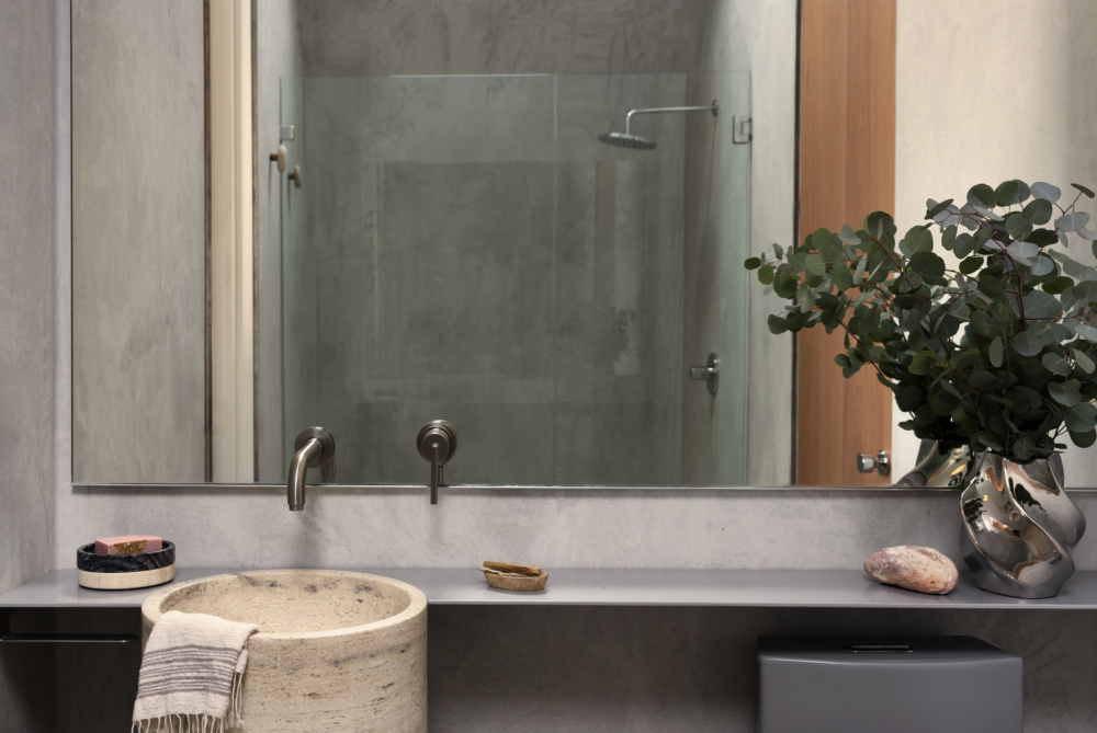 浴室則以石材洗手台、霧面金屬水龍頭和玻璃淋浴間結合。