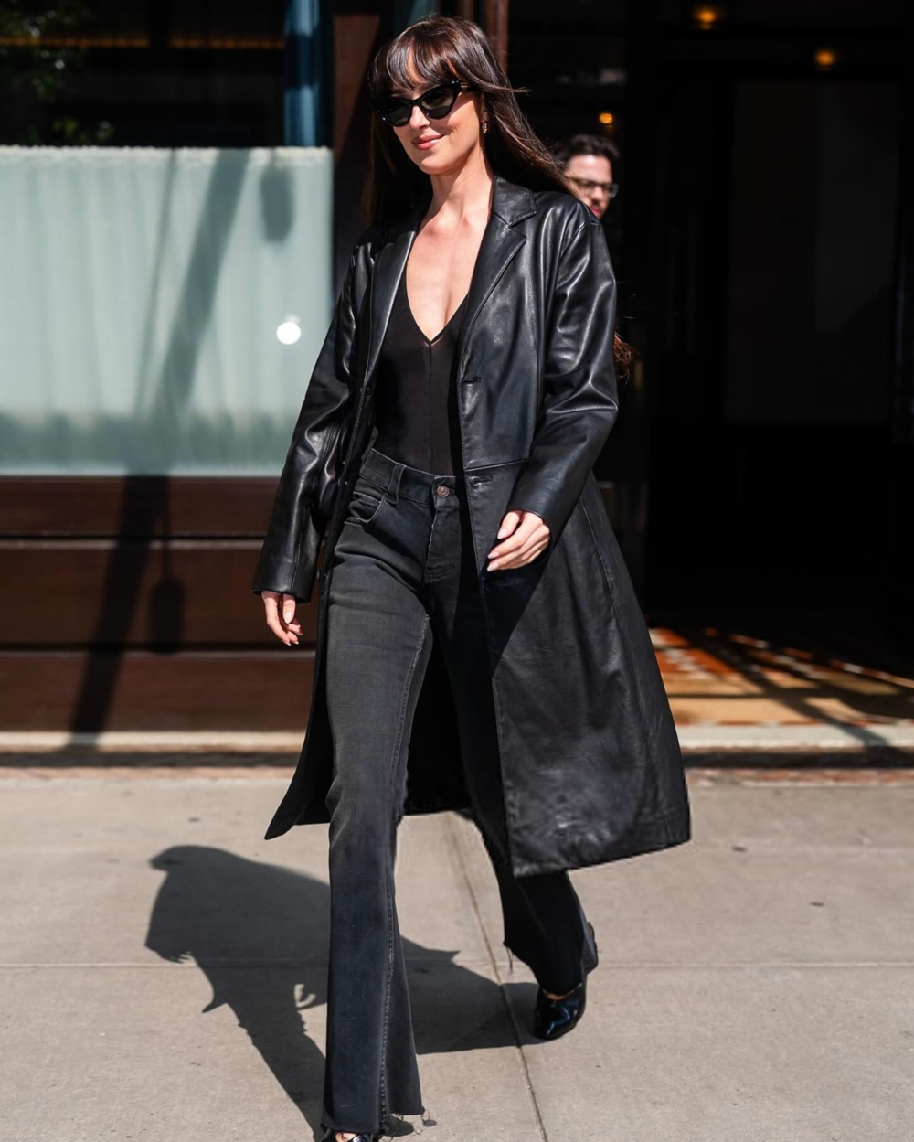 一身純黑造型亮相,身穿長款皮夾克和巴黎世家的透視深V緊身衣。她搭配了高腰黑色牛仔褲、Khaite坡跟鞋、小巧的環形耳環和一副太陽眼鏡。