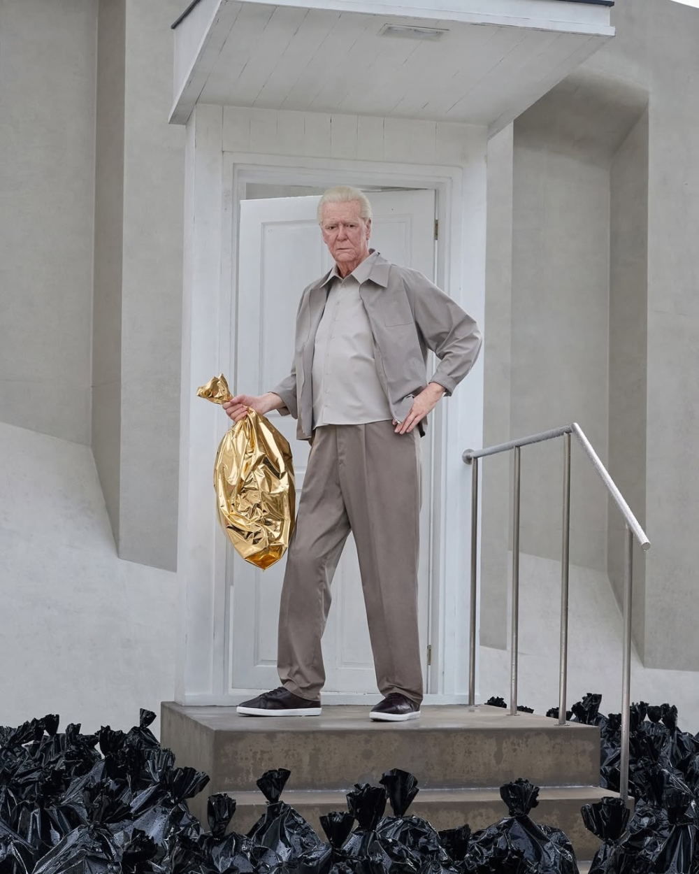 在山丘的正中央，站立著一位 手握金色袋子的老人雕像