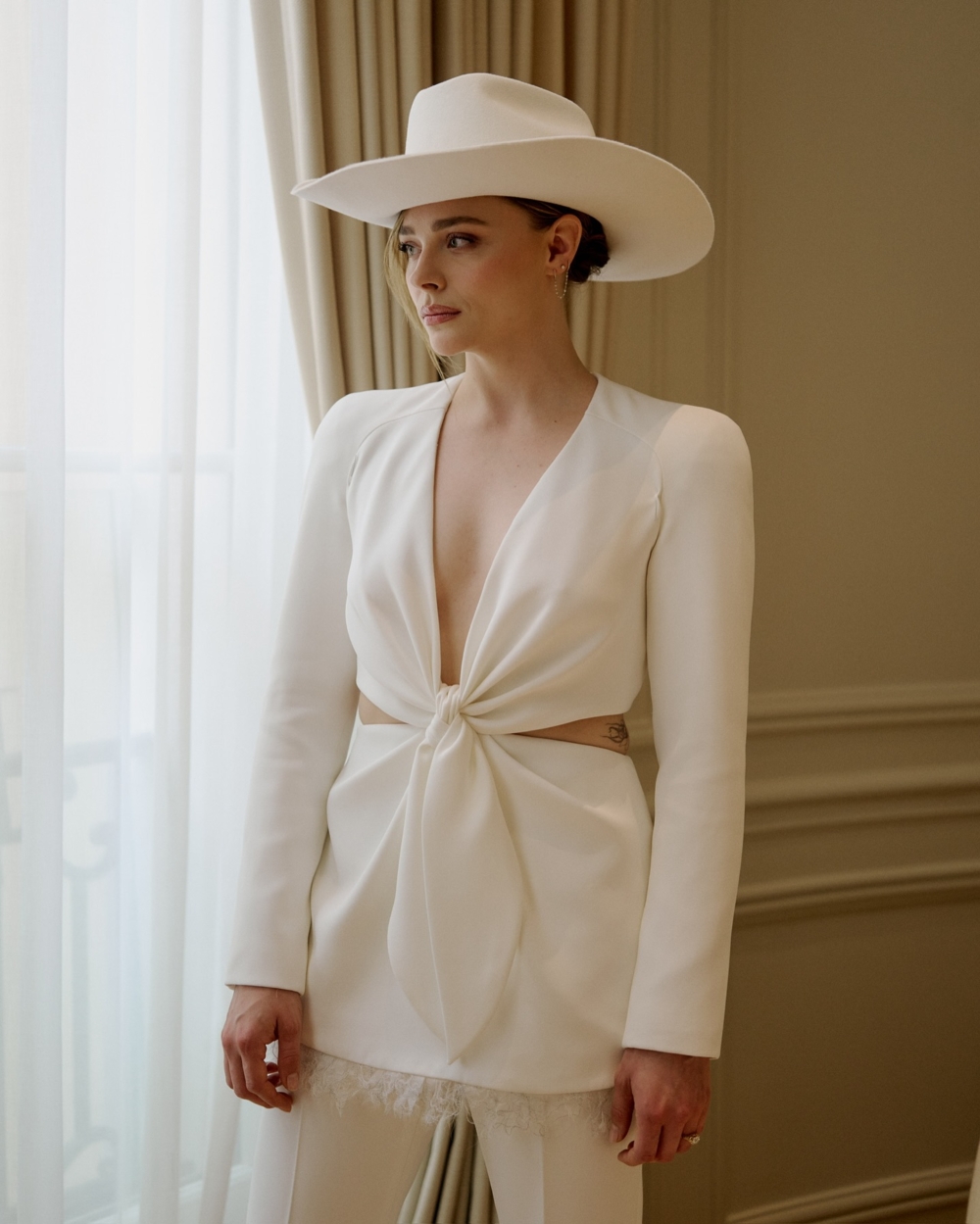 在婚禮後的派對上，Chloë 換上了一套白色剪裁西裝，腰部的鏤空設計與小扭結展現出設計師的巧思
