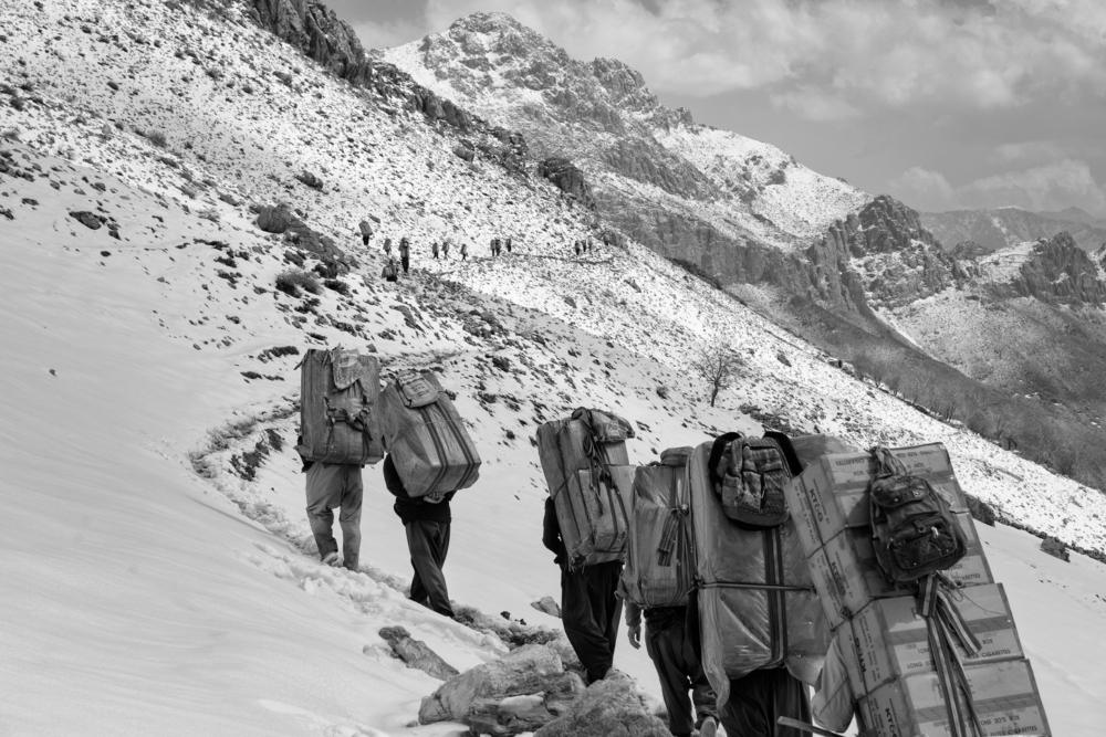 畫面中，送貨員背負著高聳的貨物，踩過積雪覆蓋的山路