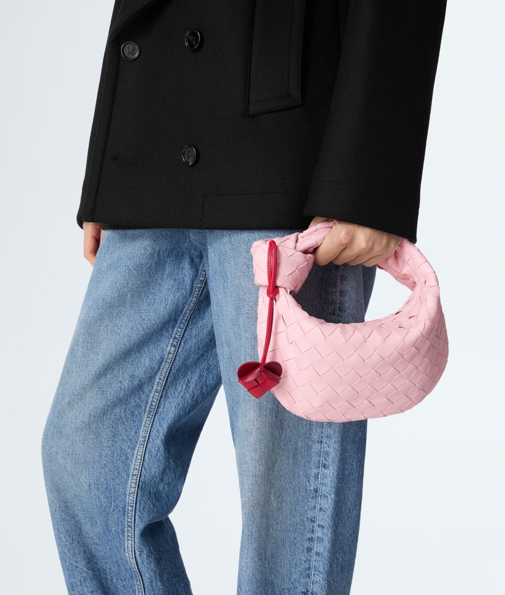 Bottega Veneta Mini Jodie最迷人之處在於本季附贈的可拆卸皮革心型吊飾，在優雅的編織線條中點綴出一抹純真的愛意