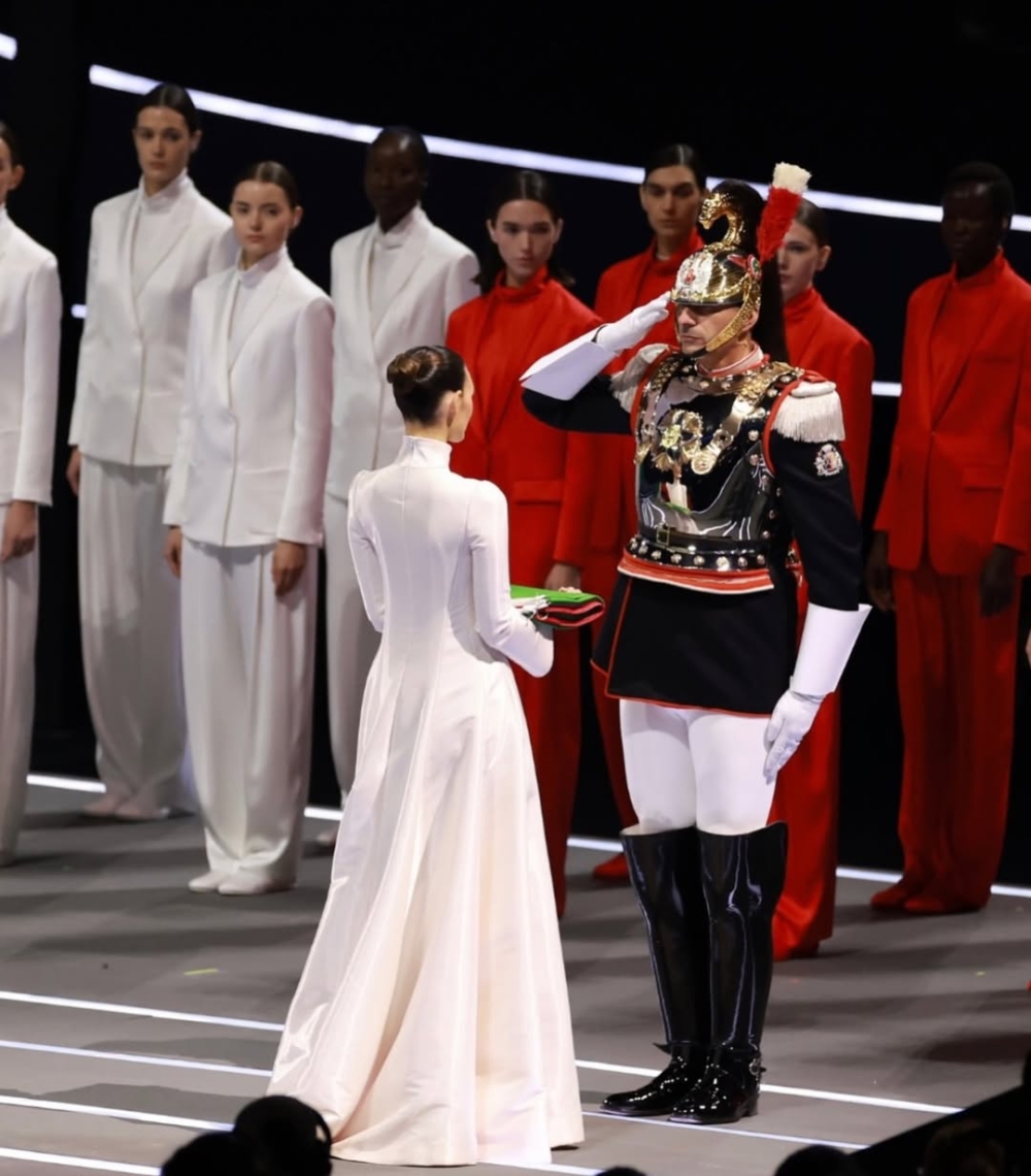 她身著一襲Giorgio Armani的極簡白色禮服，手持義大利國旗，眼神堅定而沉靜