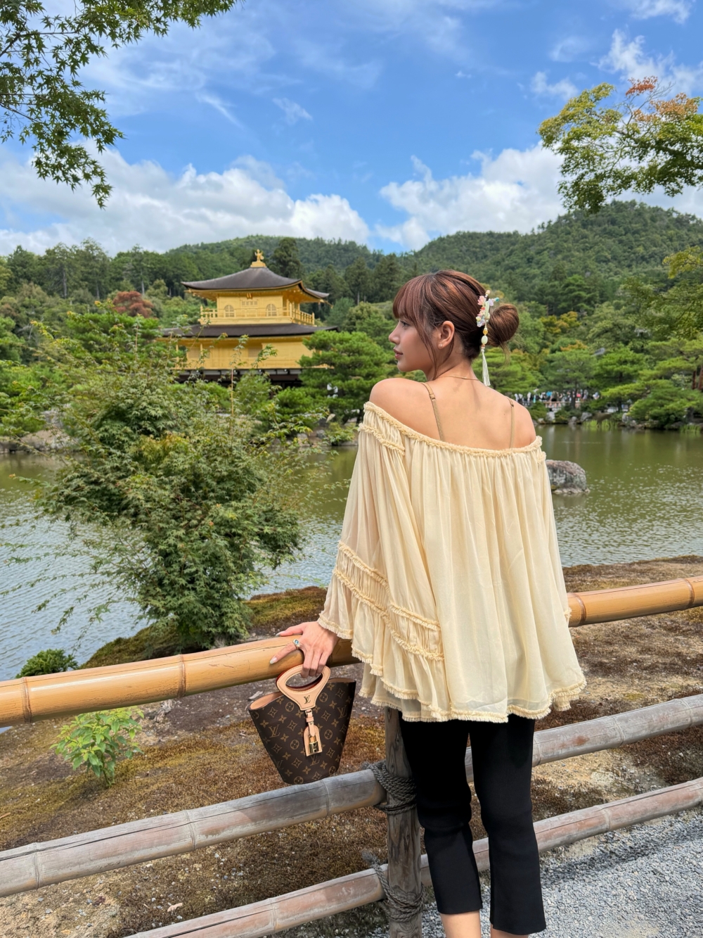 在金閣寺池畔，Lisa換上Zimmermann鵝黃色一字領上衣，荷葉邊與流蘇細節讓整體充滿浪漫氣息
